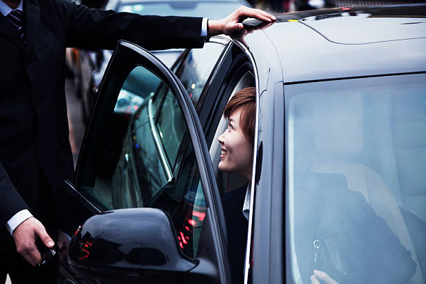 Businessman opening car door for businesswoman Businessman opening car door for businesswoman during the day in Beijing open car door stock pictures, royalty-free photos & images