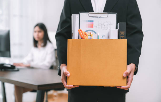 Businessman packaging and holding brown cardboard box with documents and personal office supplies because fired from work. stock photo