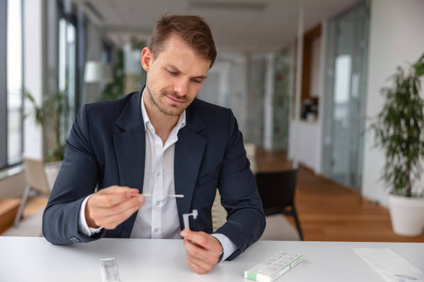 Businessman putting a swab into the solution of a self testing COVID-19 kit stock photo