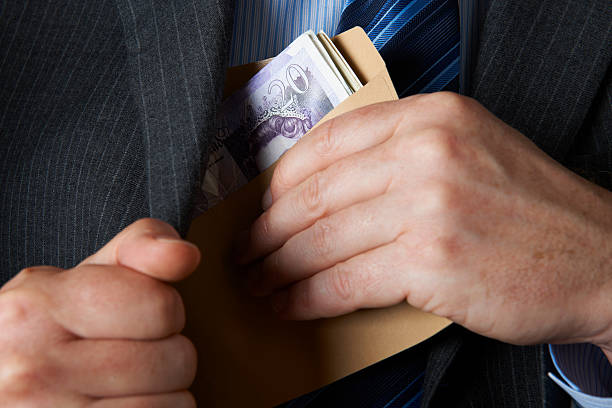 Businessman Putting Envelope Filled With Sterling In Jacket Pocket stock photo