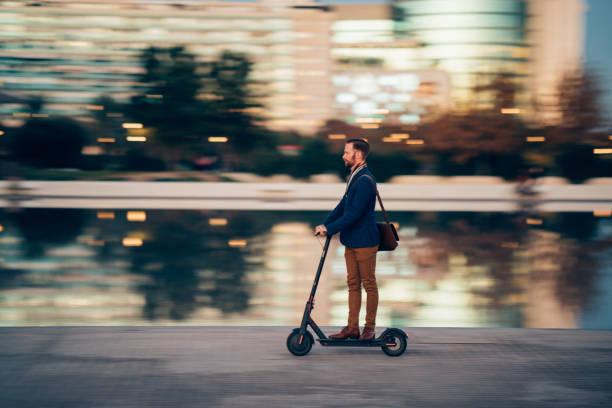 businessman riding a scooter in the city - trotinetes imagens e fotografias de stock
