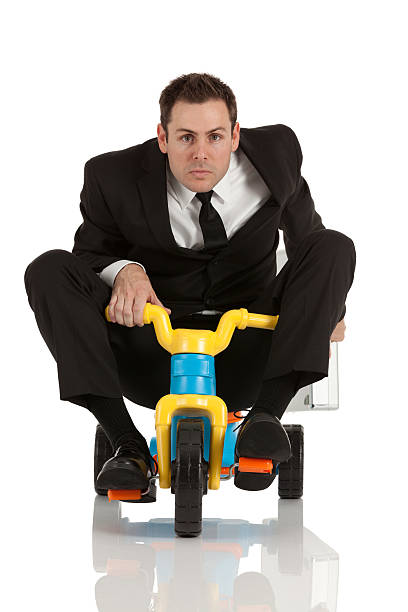 Businessman riding a tricycle Businessman riding a tricycle adult tricycle stock pictures, royalty-free photos & images