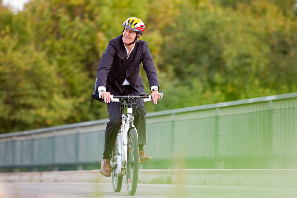 Businessman riding bicycle on bridge  electric bicycle stock pictures, royalty-free photos & images