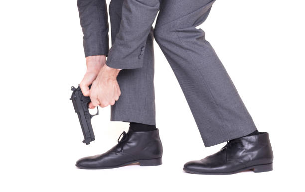 businessman-shooting-himself-in-the-foot-with-a-handgun-picture-id1064220330