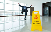 istock Businessman slipping by the warning sign 1345435137