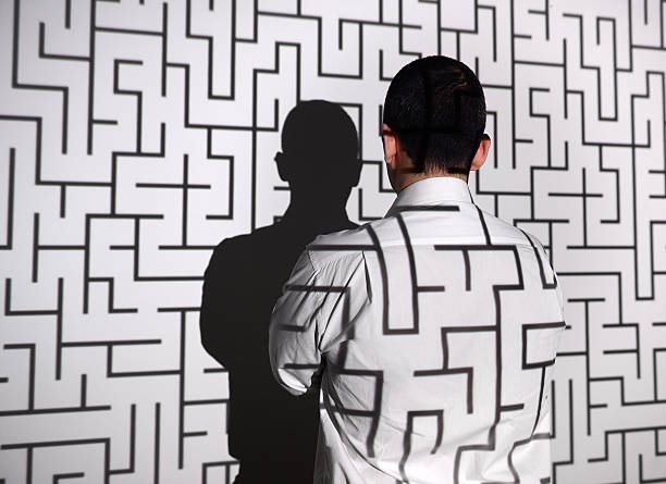 Businessman standing in front of labyrinth Businessman standing in front of projection screen. Projector reflects a labyrinth to screen and businessman's back.  maze photos stock pictures, royalty-free photos & images