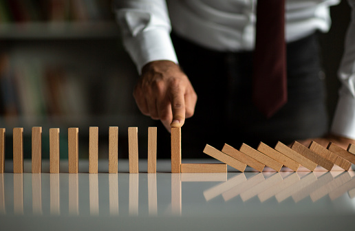Businesswoman stopping falling wooden dominoes effect