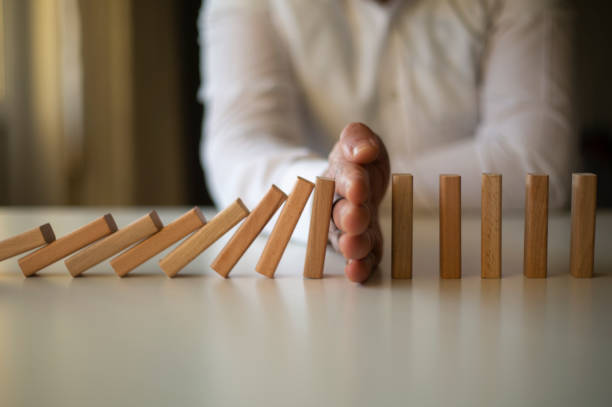 zakenman stop domino effect. risicomanagement en verzekeringsconcept - risk stockfoto's en -beelden