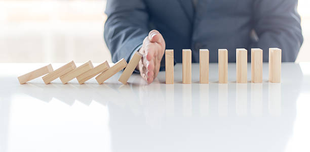 Businessman Stop Domino Effect. Risk Management and Insurance Concept Businessman Stop Domino Effect. Risk Management and Insurance Concept domino stock pictures, royalty-free photos & images