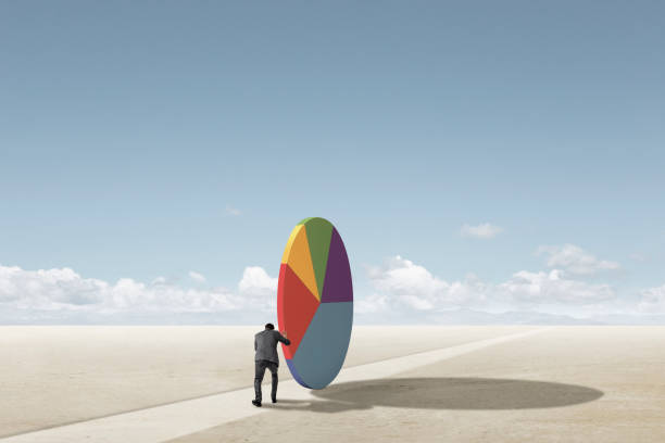 Businessman Struggling To Push Large Pie Chart Along Path To Nowhere stock photo
