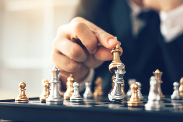 Businessman thinking about strategy concept and hand moving the king in a chess game for win. stock photo