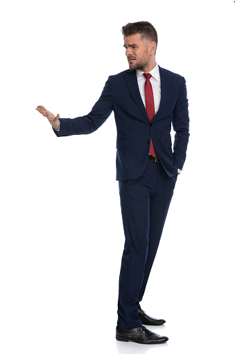 handsome businessman turning around and asking for explanations wiht one hand in pocket