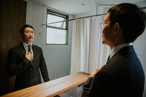 Asian businessman dressing up, grooming, before going to office in the morning.
