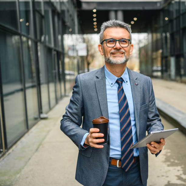 Businessman using a tablet on the city streets with coffee cup stock photo