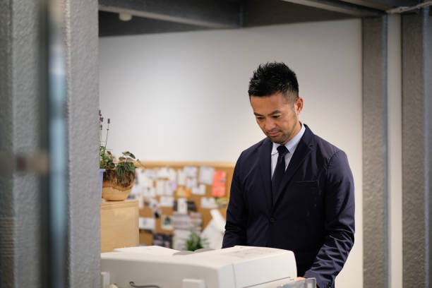 Businessman using copy machine in office businessman in forties using copy machine in office xerox photocopy machine stock pictures, royalty-free photos & images