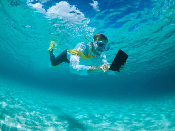 Businessman Using Digital Tablet Computer Underwater Snorkeling stock photo