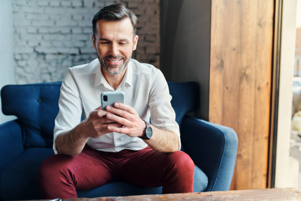 Businessman using smartphone while in cafe on lunch break stock photo