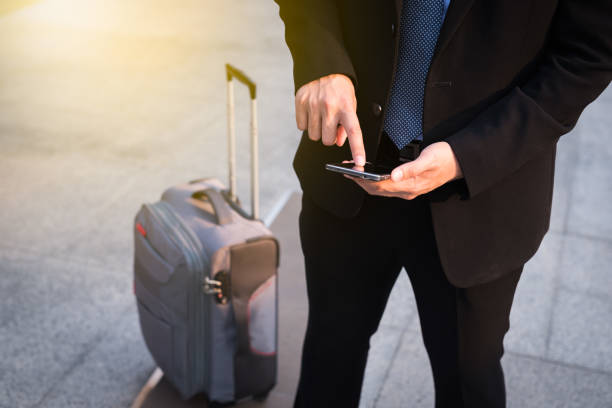 Businessman using smartphone with suitcase. stock photo