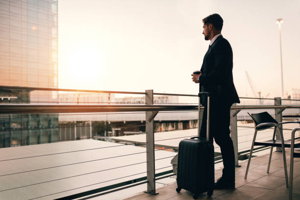 бизнесмен ждет своего рейса в зале ожидания аэропорта - business travel стоковые фото и изображения