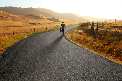 A businessman briskly walking down a country road.