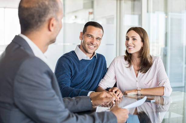 Businessman with customers Mature financial advisor showing report to young couple for their investment. Salesman and positive couple talking about purchase. Happy couple consulting financial agent for loan. mortgages and loans stock pictures, royalty-free photos & images