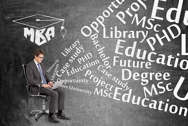 Businessman with laptop Businessman with laptop sitting on chair, MBA sign above, education words from laptop. Black background. Concept of searching information. MBA stock pictures, royalty-free photos & images