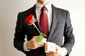 赤いバラの花を持つビジネスマン。