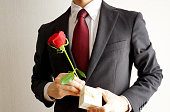 赤いバラの花を持つビジネスマン。