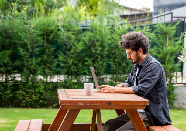 Businessman working on laptop at backyard of his house stock photo