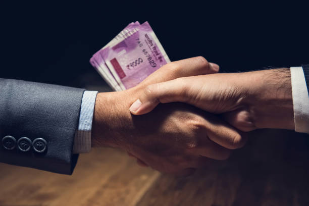 Businessmen making handshake with money, Indian Rupee currency, in hands Businessmen making handshake in dark private room with money, Indian Rupee currency, in hands - bribery and corruption concept INDIA CURRENCY  stock pictures, royalty-free photos & images
