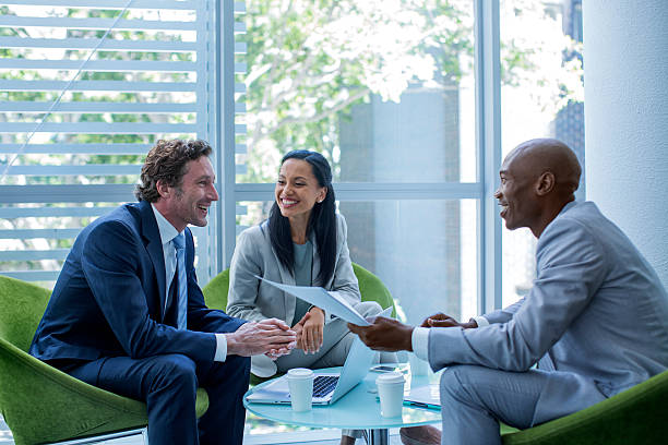 Businesspeople discussing in office Happy multi-ethnic businesspeople discussing in office three people stock pictures, royalty-free photos & images