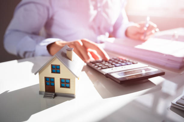 Businessperson Calculating Property Tax Close-up Of A Person Hand Doing Property Tax Calculation With House Model On The Table real estate stock pictures, royalty-free photos & images