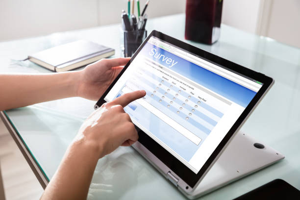 businessperson füllt online-umfrageformular auf digitalen laptop - fragebogen stock-fotos und bilder