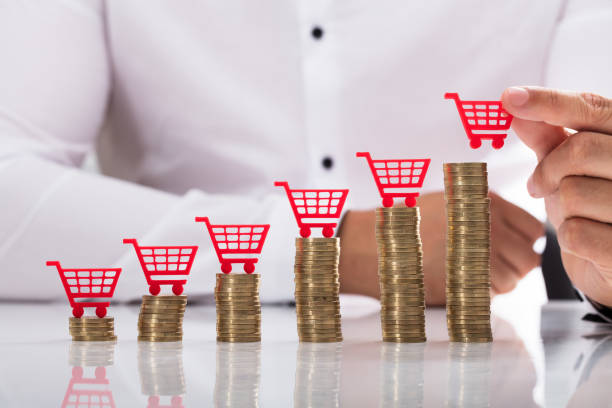 Businessperson placing shopping cart over stacked coins Businessperson's hand placing red shopping cart over increasing stacked coins inflation stock pictures, royalty-free photos & images