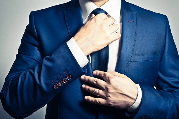 Businesswear Businessman in blue suit adjusting his tie necktie stock pictures, royalty-free photos & images