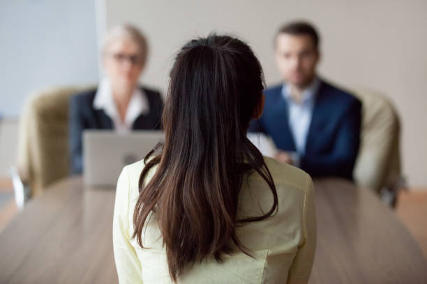 Businesswoman and businessman HR manager interviewing woman Businesswoman and businessman HR manager interviewing woman. Candidate female sitting her back to camera, focus on her, close up rear view, interviewers on background. Human resources, hiring concept candidate stock pictures, royalty-free photos & images