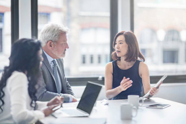 Businesswoman discussing with colleagues in office Businesswoman discussing with colleagues. Entrepreneurs are planning in board room. They are sitting at table in office. board room photos stock pictures, royalty-free photos & images