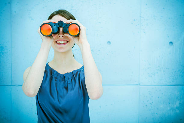 businesswoman holding binoculares - descubrimiento fotografías e imágenes de stock