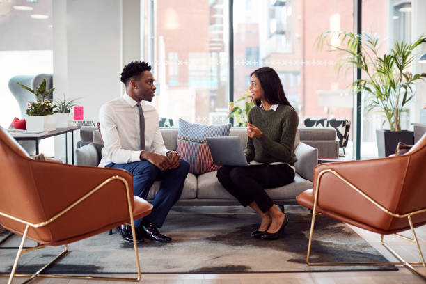 Businesswoman Interviewing Male Job Candidate In Seating Area Of Modern Office Businesswoman Interviewing Male Job Candidate In Seating Area Of Modern Office job interview stock pictures, royalty-free photos & images