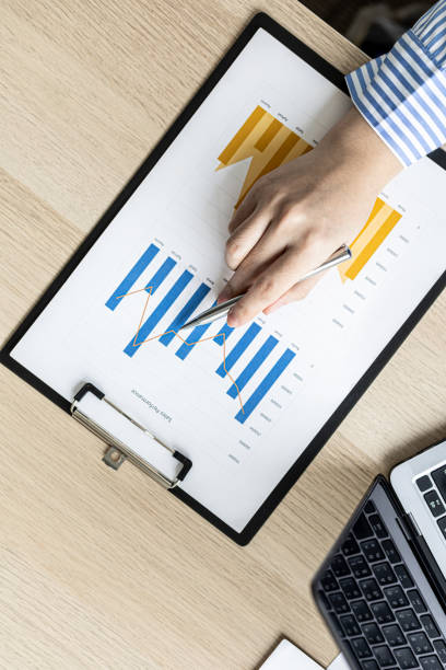 A businesswoman is reviewing the sales summary sheet from the sales department, she is reviewing the data and analyzing the sales data to plan to manage more sales growth. Sales management concept. stock photo