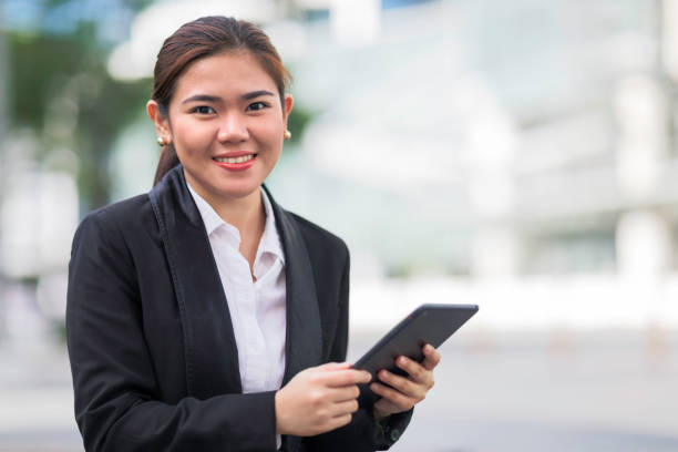 Businesswoman A woman outdoors in an office park holding a tablet. filipino woman stock pictures, royalty-free photos & images