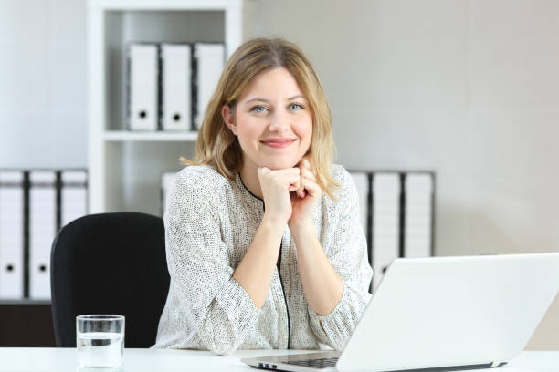 Businesswoman posing looking at you at office Front view portrait of a businesswoman posing looking at you on a desk at office secretary stock pictures, royalty-free photos & images