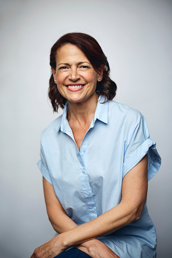 Portrait of businesswoman smiling. Confident executive is wearing blue shirt. Female professional is smiling over white background.
