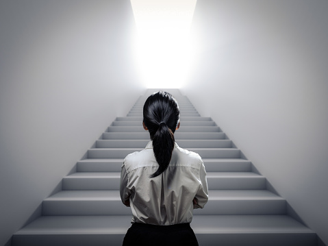 Rear view businesswoman standing at staircase