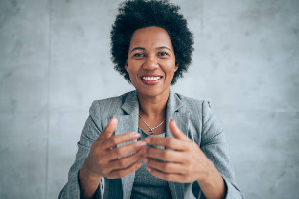 Businesswoman talking during video call in the office. African-american elegant female entrepreneur discussing while having a conference call in the office. Portrait of confident ethnicity female employee looking at camera talking on video call in the office. female video chat stock pictures, royalty-free photos & images