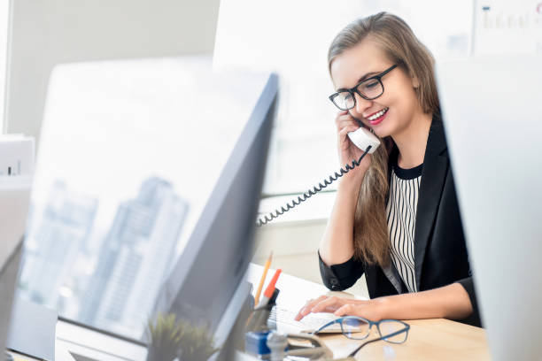 Businesswoman talking on the phone with customer at work Happy businesswoman as a customer care representative talking on the phone at work with her client in the office assistant stock pictures, royalty-free photos & images