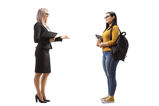 Businesswoman talking to a female student with books and backpacks