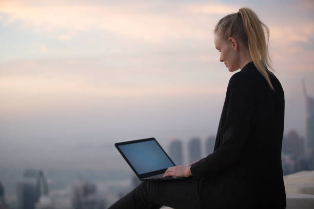 empresária usando um laptop enquanto senta sozinha pacificamente em um telhado. estudo online, trabalho e negócios. - serviço de bordo - fotografias e filmes do acervo