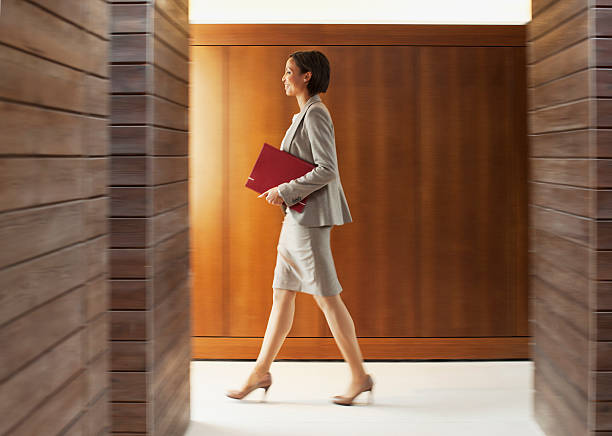donna d'affari con la cartella a piedi nel corridoio in ufficio - corridoio ufficio foto e immagini stock