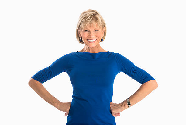 Businesswoman With Hands On Hip Over White Background Portrait of happy mature businesswoman with hands on hip standing over white background bangs hair stock pictures, royalty-free photos & images